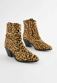 Kotníkové boty s leopardským vzorem vyrobené z měkkého semiše, s špičatou špičkou, blokovým podpatkem a bočními zipy pro snadné nazouvání.
