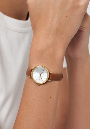 Bruine leren horlogeband met een ronde goudkleurige kast, een witte wijzerplaat en minimalistische uurmarkeringen. Simpel en elegant ontwerp.