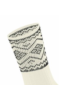 Stricksocke in Creme mit schwarzem geometrischem Muster. Verfügt über eine gerippte Textur am oberen Rand und eine glatte Oberfläche am Schaft.