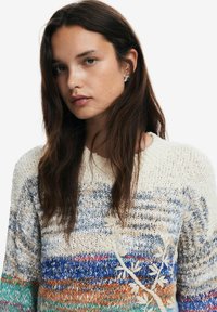 Többszínű kötött pulóver kék, zöld, narancs és krémszínű csíkokkal, virágmintás hímzéssel és kerek nyakkivágással. Puha tapintású.