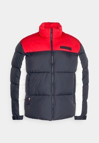 Pohodlná bunda s vysokým límcem, vyrobená z červených, námořnických a bílých barevných bloků. Zahrnuje zip vpředu a postranní kapsy, s logem na hrudi.