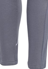 Graue sportliche Leggings mit glatter Textur, versehen mit weißen Akzentnähten und einem dezenten Seitentaschen-Detail. Enganliegendes Design entlang des gesamten Beins.