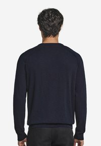 Marinblå tröja med lång ärm och ribbade manschetter. Har rundad halsringning och raglanärmar. Mjuk, strukturerad tyg.