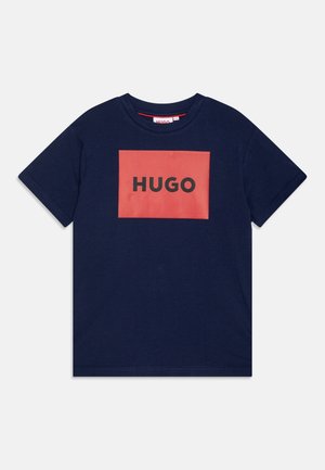 Navy blue cotton t-shirt with a coral rectangular logo featuring the word "HUGO" in bold black letters on the front. Short sleeves, crew neck.