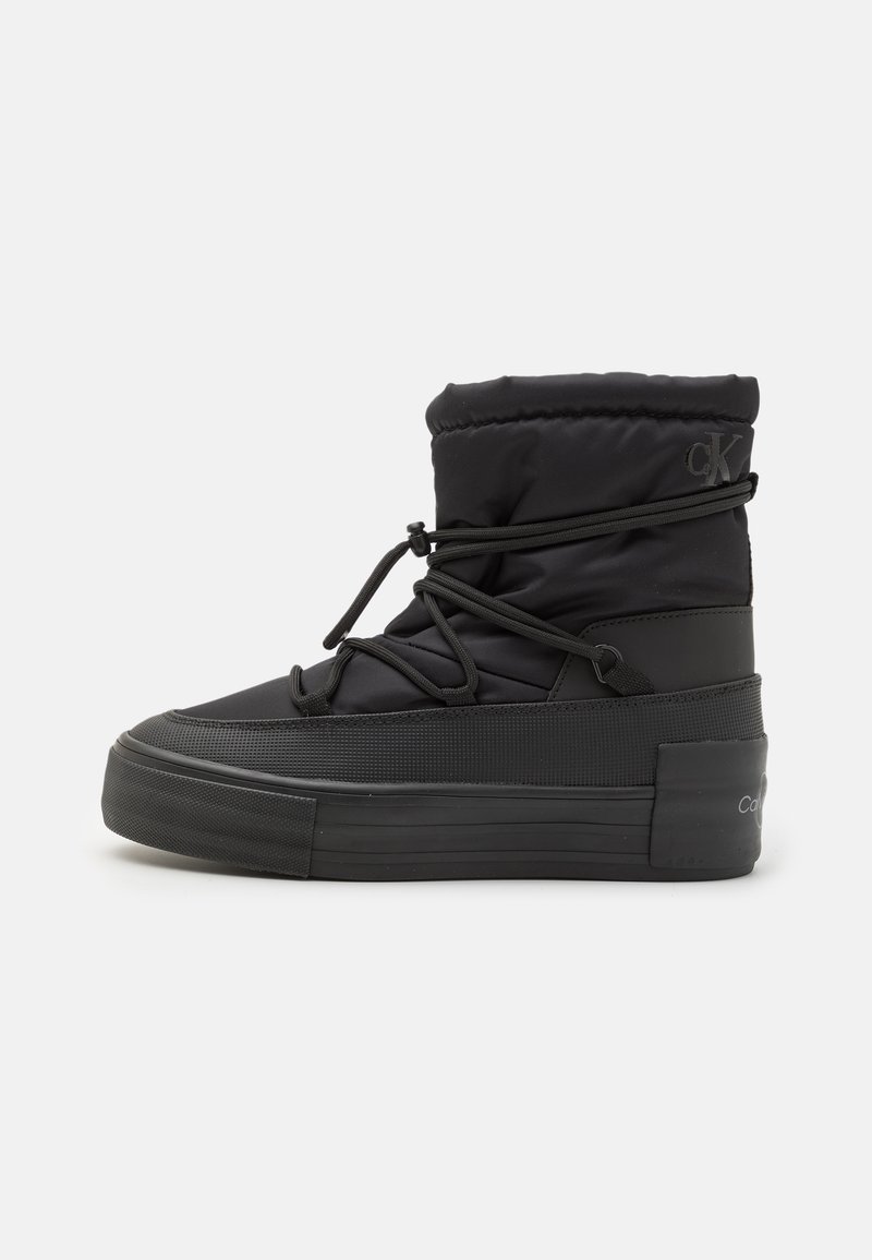 Černá kotníková bota s prošívaným nylonovým svrškem, gumovou podrážkou a zvýšenou platformou. Obsahuje design šněrování s toggle knoflíky a logo na boku.