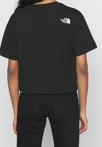 Svart kort t-shirt i bomull. Har korta ärmar och en vit logo på övre delen av ryggen. Matchas med svarta byxor.