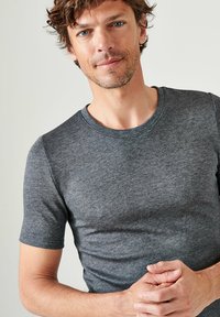 Camiseta gris de manga corta hecha de una tela suave, con un escote redondo y un diseño ajustado, sin patrones ni acentos visibles.