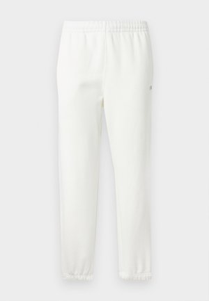 White cotton sweatpants with an elastic waistband and tapered legs. Features a small logo detail on the side. Soft texture, minimal design.