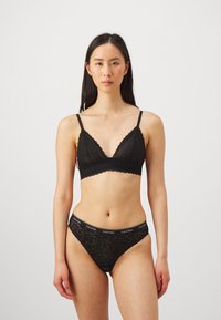 Svart blonderbralett med bølgete kanter og justerbare stropper, kombinert med matchende blonder-bikiniunderdeler med en merket midjebånd.