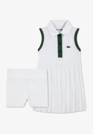 Robe polo blanche avec accents verts, jupe plissée et fermeture à trois boutons. Comprend un short blanc assorti pour plus de couvrance.