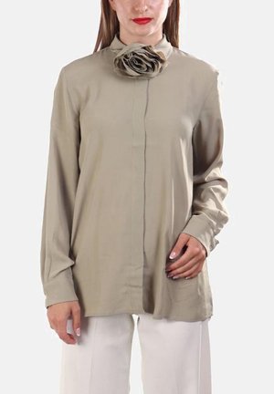 Blusa beige con maniche lunghe, colletto alto e un grande accento floreale sul petto. Tessuto morbido e silhouette dritta.