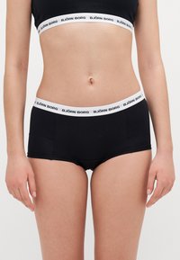 Μαύρα βαμβακερά σλιπάκια hipster με λευκή ελαστική ζώνη που φέρει το κείμενο "BJÖRN BORG" σε μαύρο χρώμα. Λείο υλικό, εφαρμοστή σχεδίαση.