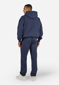 Navy blue hooded sweatshirt and matching sweatpants, cotton blend material, adjustable drawstring on hood, ribbed cuffs and waistband.
