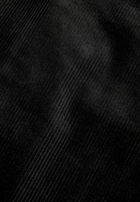 Tissu en velours côtelé noir avec une texture douce, présentant des côtes subtiles parallèles et une couleur uniforme dans l'ensemble.