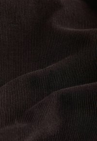Ciemnobrązowy prążkowany materiał o miękkiej teksturze, z naturalnymi zagięciami i delikatnym połyskiem, podkreślający falistą powierzchnię i głębię.