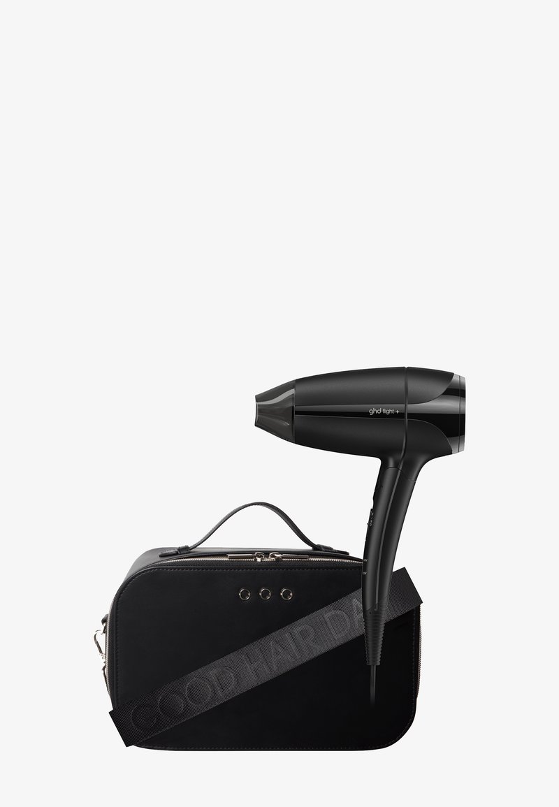 Sèche-cheveux compact noir avec embout buse, posé sur une housse de transport noire avec fermeture éclair, poignée et sangle d'épaule.