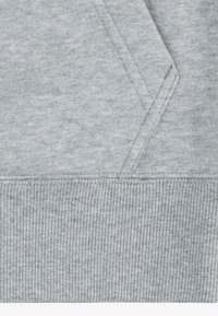 Tejido de sudadera gris claro con dobladillo acanalado y costuras laterales. La textura es suave y ligeramente texturizada, con una superficie uniforme.