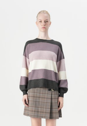 Strikket genser i lilla, krem og mørk grå striper; oversized passform med ribbet tekstur. Kombinert med et rutete skjørt med sidebelte.
