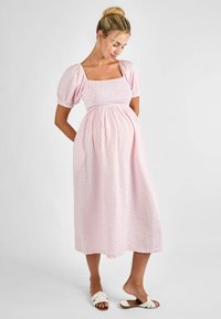 Ružičasta gingham midi haljina s kvadratnim izrezom, napuhanim rukavima i smockanim tijelom. Sadrži lepršavu suknju i bočne džepove.