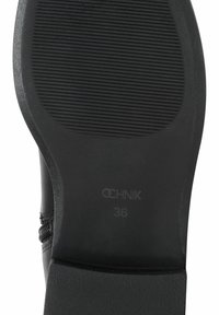 Czarna podeszwa buta z teksturowanymi żłobieniami, charakteryzująca się gładkim wykończeniem i subtelnym oznaczeniem "OCHNIK 36". Krzywizna konstrukcji zapewniająca lepszy komfort.