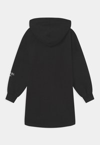 Černé dlouhé mikinové šaty s kapucí, dlouhými rukávy, elastickými manžetami a bílým textem potisknutým na levém rukávu blízko zápěstí.