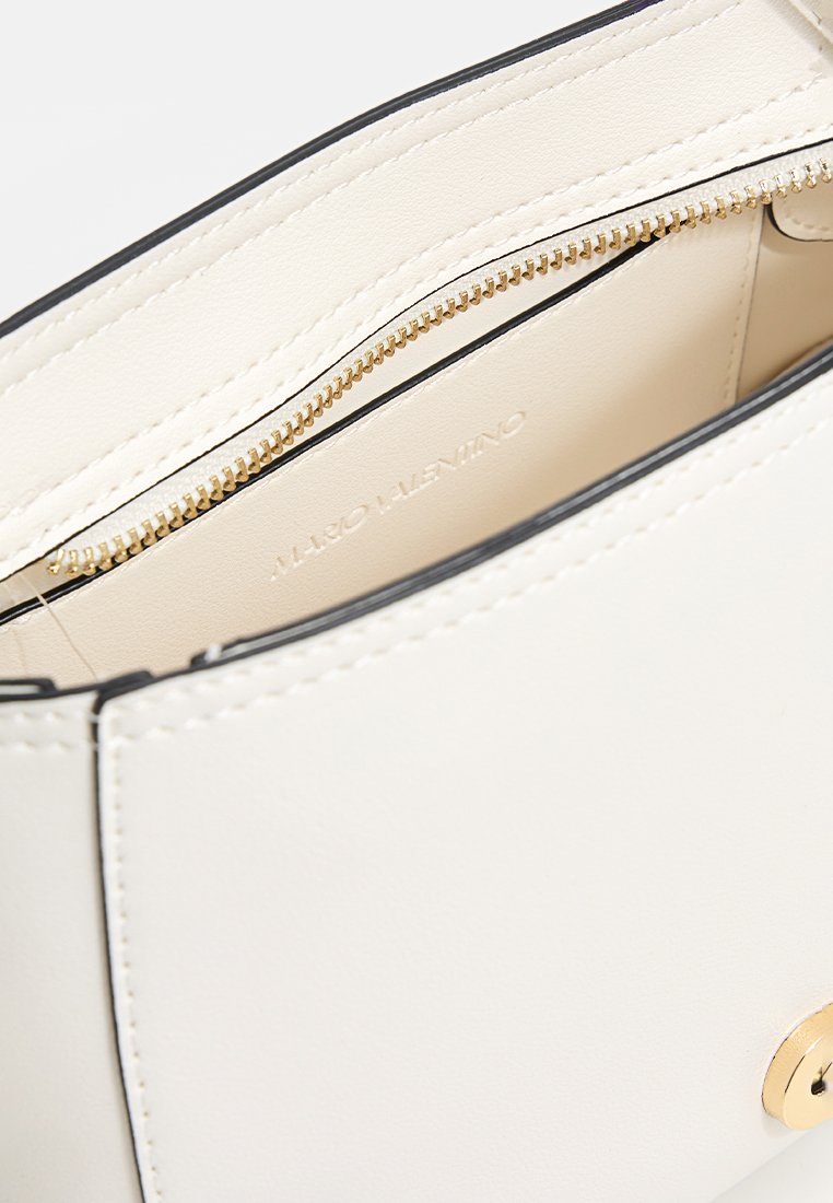 Intérieur d'un sac à main en cuir blanc avec fermeture éclair dorée, bord noir et logo embouti. Texture lisse et lignes épurées.