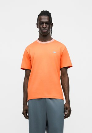 Maglietta di cotone arancione con collo rotondo e maniche corte. Presenta un piccolo logo blu sul petto e una bordatura del collo a contrasto.
