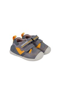 Zapatos infantiles grises y naranjas con dos correas de Velcro, hechos de material sintético, con una suela de goma redonda y costuras en contraste.