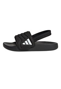 Černá pantofle na kluzáku s gumovou podrážkou, polstrovaným páskem s texturovaným vzorem a třemi bílými pruhy na straně. Lehká a nastavitelná.