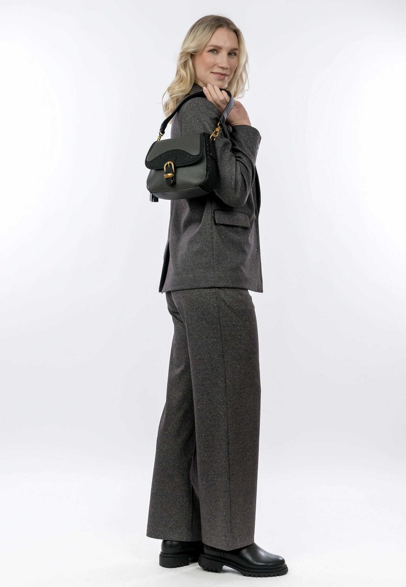 Blazer grigio su misura e pantaloni a gamba larga, abbinati a una piccola borsa nera con hardware dorato e finitura testurizzata.