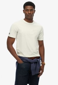 T-shirt en coton vert clair à manches courtes et col rond. Présente un logo en relief sur la poitrine et un sweat à capuche bleu marine noué à la taille.