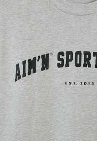 Šedé bavlněné tričko s černým obloukovým logem "AIM'N SPORT" a nápisem "EST. 2013" pod ním. Hladká textura, standardní design s kulatým výstřihem.