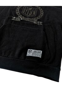Schwarzer Hoodie aus weichem Material mit NFL-Logo, einem dekorativen Lorbeerkranz und einem ‚Recovered‘-Label auf der Tasche sowie gerippten Bündchen.