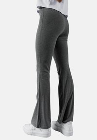 Szare spódnice w kształcie dzwonów wykonane z miękkiego, elastycznego materiału. Posiadają gładką teksturę i wysoki stan dla komfortu, w zestawieniu z białymi sneakersami.