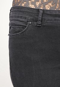Svarta denimjeans med slim fit, som har en traditionell femfickorsdesign, subtila sömmar och en slät yta.