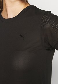 Černé sportovní tričko s krátkými síťovanými rukávy, s kulatým výstřihem a výrazným černým logem Puma na hrudi.