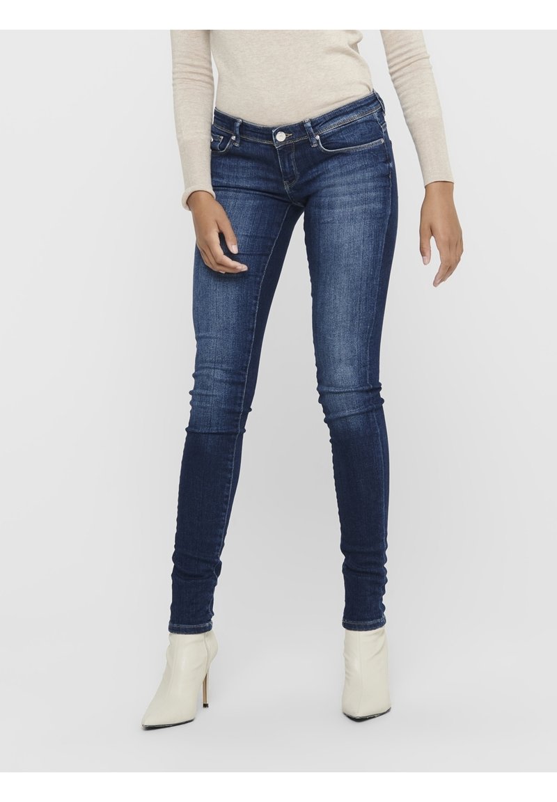 Džíny typu skinny vyrobené z tmavě modrého denimu, s mid-rise pasem, pětikapsovým designem a mírným blednutím na stehnech. Hladká textura.