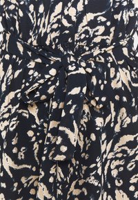 Robe à motif abstrait noir et beige, avec une ceinture en tissu nouée en nœud à la taille et des boutons sur le devant.