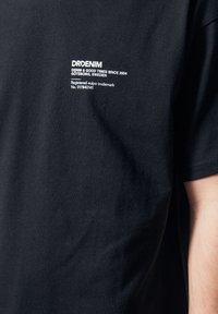 Camiseta de algodón negra con un logo impreso en blanco en el pecho que dice "DRDENIM, DENIM & GOOD TIMES SINCE 2004, GÖTEBORG, SUECIA."