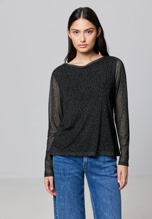 Haut noir à manches longues avec imprimé léopard, manches semi-transparentes, encolure arrondie et coupe décontractée, associé à un jean en denim bleu.