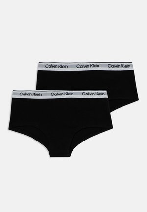 Dve čierne hipsterské nohavičky Calvin Klein s bielymi elastickými pásmi v páse so čiernym logom Calvin Klein.
