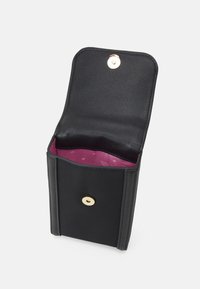 Černá kožená peněženka se zapínáním na patentku. Uvnitř má růžovou podšívku se vzory hvězd. Kompaktní obdélníkový design, hladká textura.