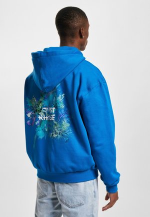 Blue hooded sweatshirt with a vibrant floral pattern and the words "JUST RISE" printed on the back. Material appears soft and fleece-lined.