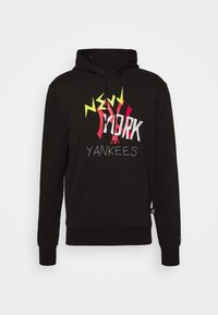 Černá fleecová mikina s kapucí a přední kapsou typu kangaroo. Na přední straně je nápis "NEW YORK" v tučném bílém, červeném a zeleném písmu s texturovaným povrchem.