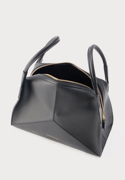 Μαύρη δερμάτινη τσάντα χειρός με δομημένο γεωμετρικό σχέδιο, χρυσλό φερμουάρ μερικώς ανοιχτό και δύο καμπυλωτές λαβές σε λευκό φόντο.