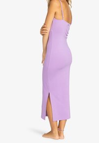 Lavendelfarbenes Midikleid aus weichem Stoff, mit dünnen Trägern, einem seitlichen Schlitz und einer figurbetonten Silhouette.