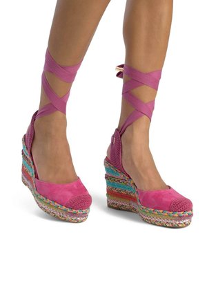 Tacchi a zeppa con tomaia in suede rosa e accenti lavorati a maglia. La suola in espadrilles intrecciata e colorata aggiunge texture e interesse visivo.