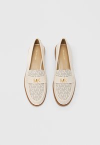 Beige slip-on sko med MK-logo mønster på stoffets overdel, læderrem og guldfarvet beslag. Brun gummisål.