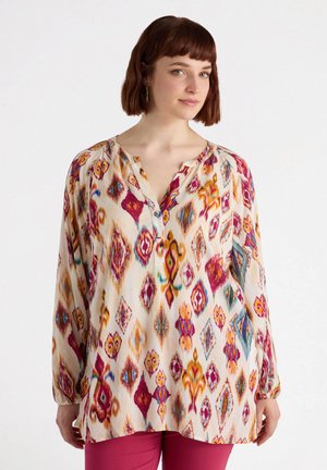 Blusa de manga larga en tejido ligero, con un colorido patrón geométrico de diamantes y espirales en tonos de rosa, amarillo y azul.