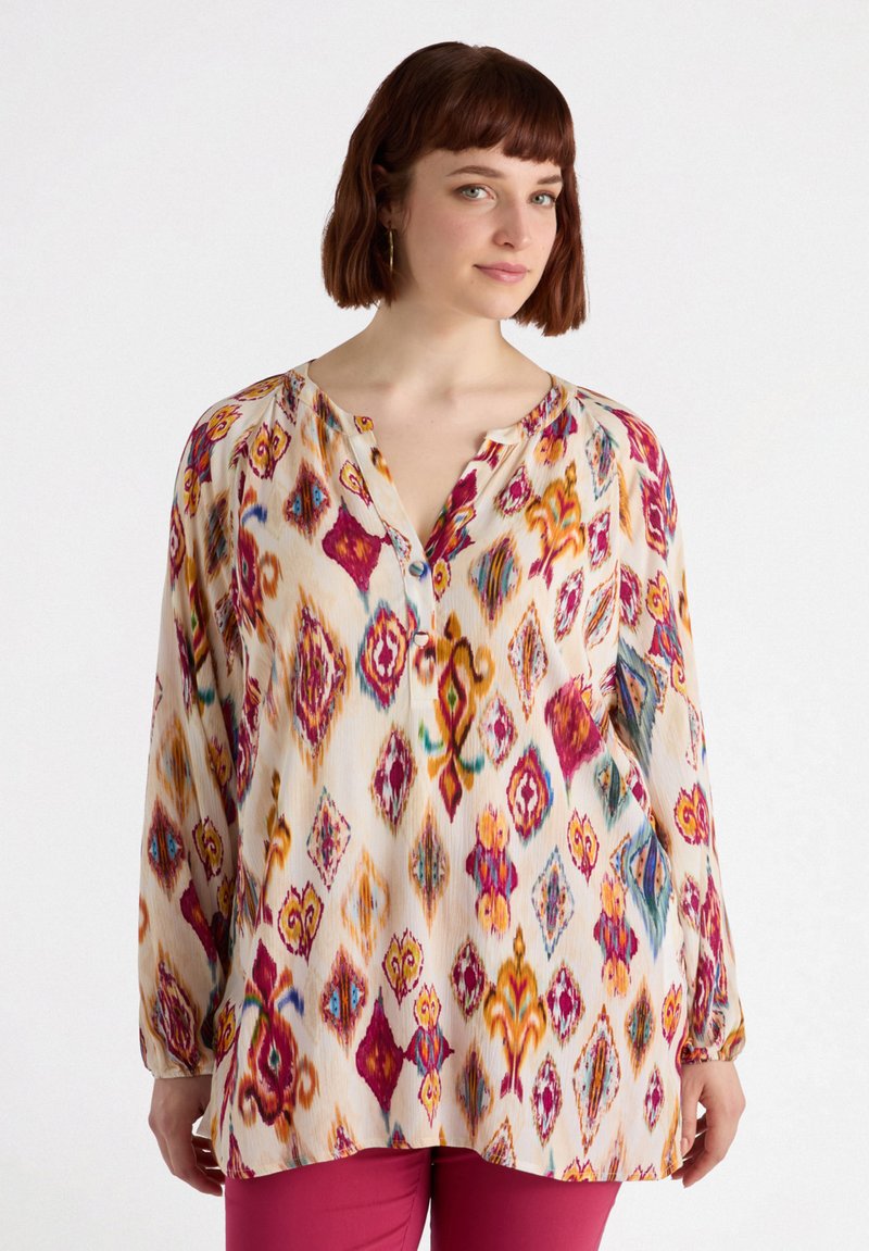 Långärmad blus i lätt tyg, med ett färgglatt geometriskt mönster av diamanter och virvlar i rosa, gult och blått.